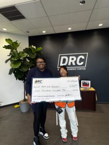 Two ladies standing with a scholarship check