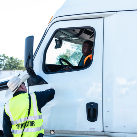 CDL instructor talking to CDL student in cab of white truck